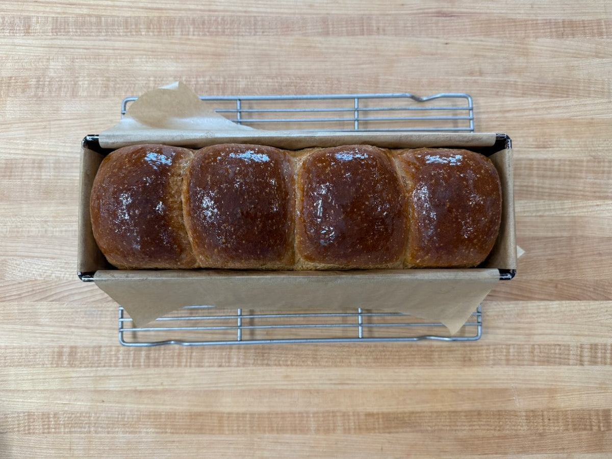 Freshly baked white bread loaf with golden crust, sliced to show soft open crumb