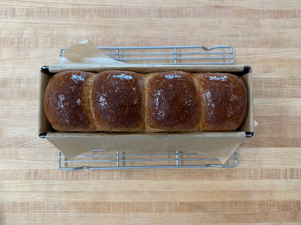 Freshly baked white bread loaf with golden crust, sliced to show soft open crumb