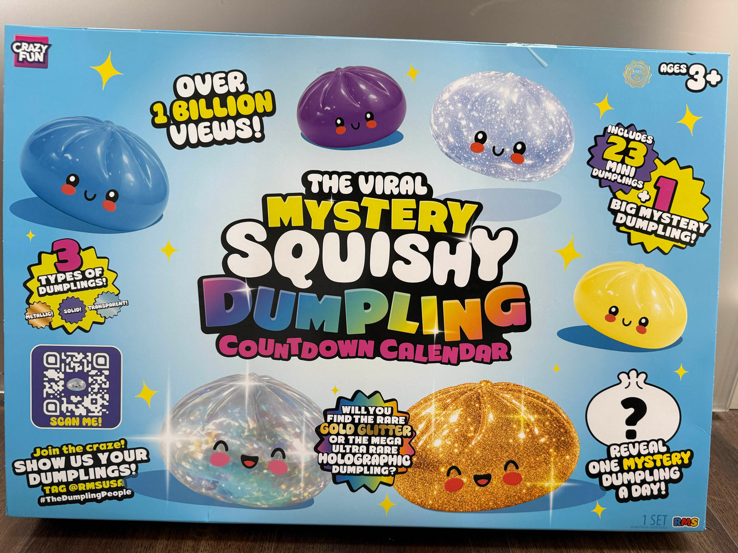 The Viral Mystery Squishy Dumpling Countdown Calendar box by Crazy Fun, featuring a bright blue background with cartoonish squishy dumpling illustrations in blue, purple, white, yellow, and glittery gold.