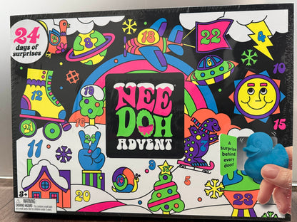 A colorful NEE DOH Advent box with a hand opening one of the numbered surprise doors. The box features a vibrant, cartoon-style illustration with 24 days of surprises text and a blue dinosaur surprise peeking out.