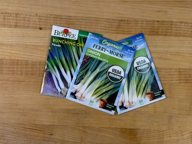 Three seed packets for onions on a wooden surface